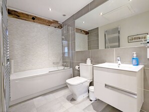 Une salle de bain moderne avec une douche à parois de verre, des toilettes blanches et un meuble-lavabo avec un miroir.