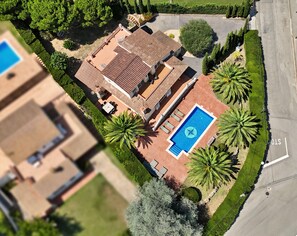 Vue aérienne d’une propriété résidentielle dotée d’une piscine, de meubles de patio et de palmiers.