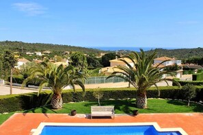 Une piscine avec un banc, des palmiers et des maisons en arrière-plan.