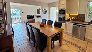 Een moderne keuken met een eetgedeelte, met een houten tafel, stoelen en een inbouwoven.