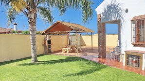 Un espace extérieur aménagé avec un barbecue, une table en bois et un banc.