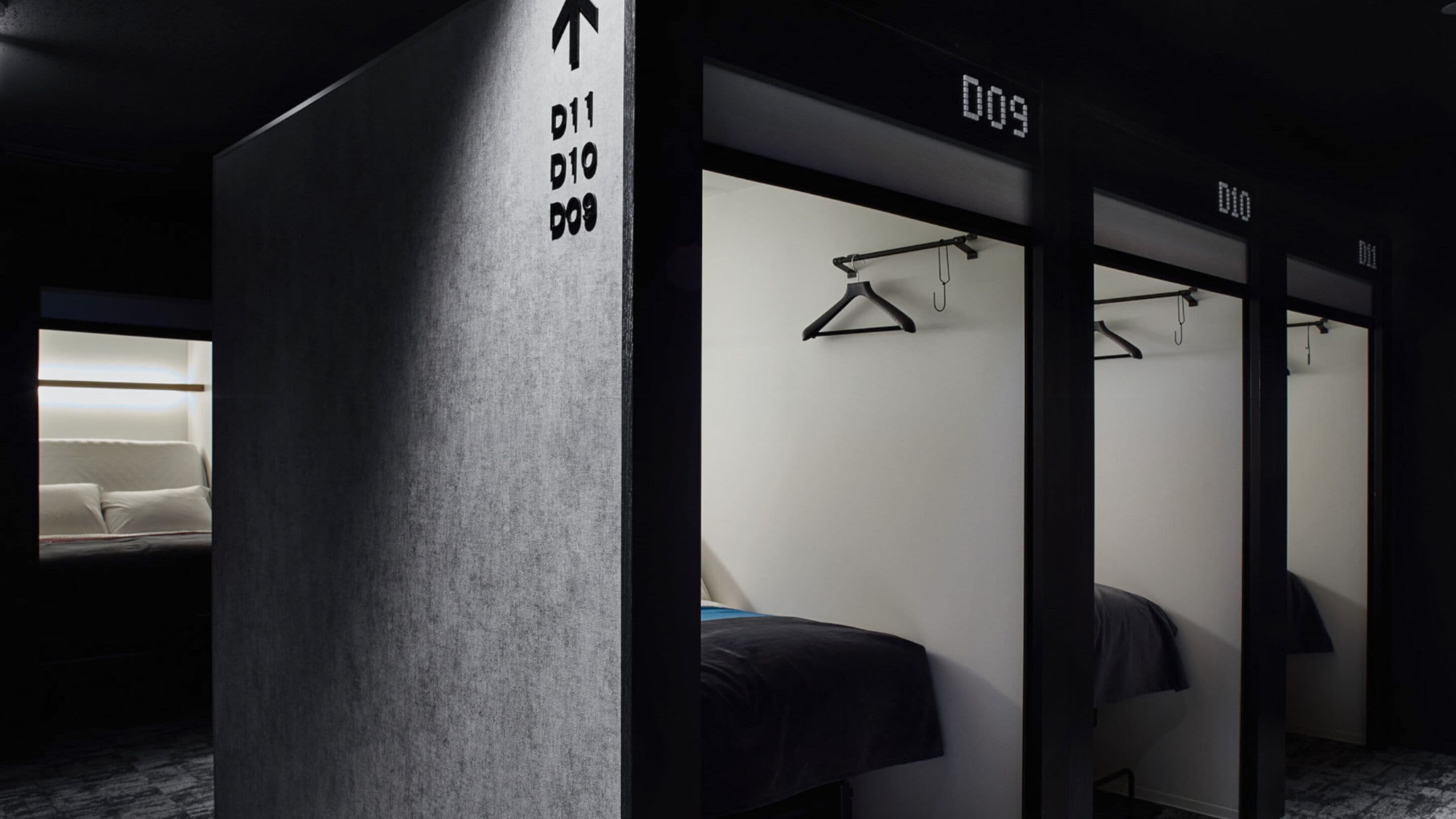 A hotel room with a bed, a desk, and a wardrobe. There are signs indicating the room number and direction to the bathroom.