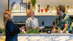 A coffee shop counter with a marble top, a menu stand, and various plants and books in the background. - The Millennials Shibuya (Tokyo)