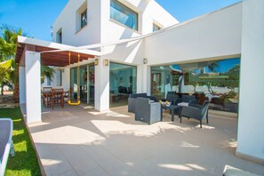 A modern outdoor patio area with a dining set and lounge chairs. - Villa Athos - PlusHolidays (Calpe)