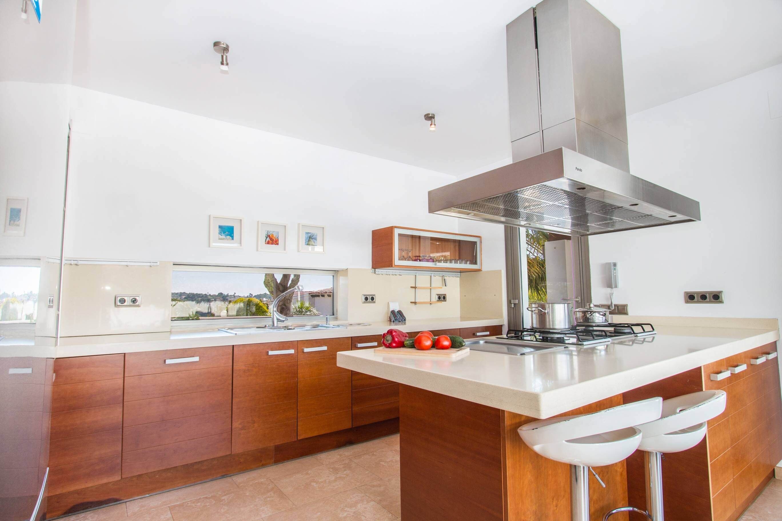 A modern kitchen with a central island, stainless steel appliances, and a large range hood.