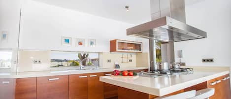 A modern kitchen with a central island, stainless steel appliances, and a large range hood.