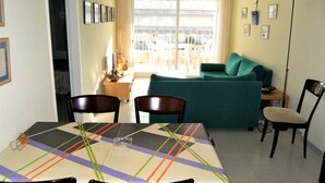 Un comedor con una mesa dispuesta para dos personas, un sofá y una silla.