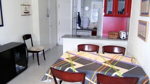 Un comedor con una mesa dispuesta para cuatro, un mueble negro y una silla.