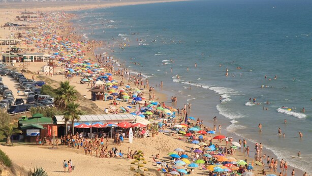 A crowded beach with numerous umbrellas and people.