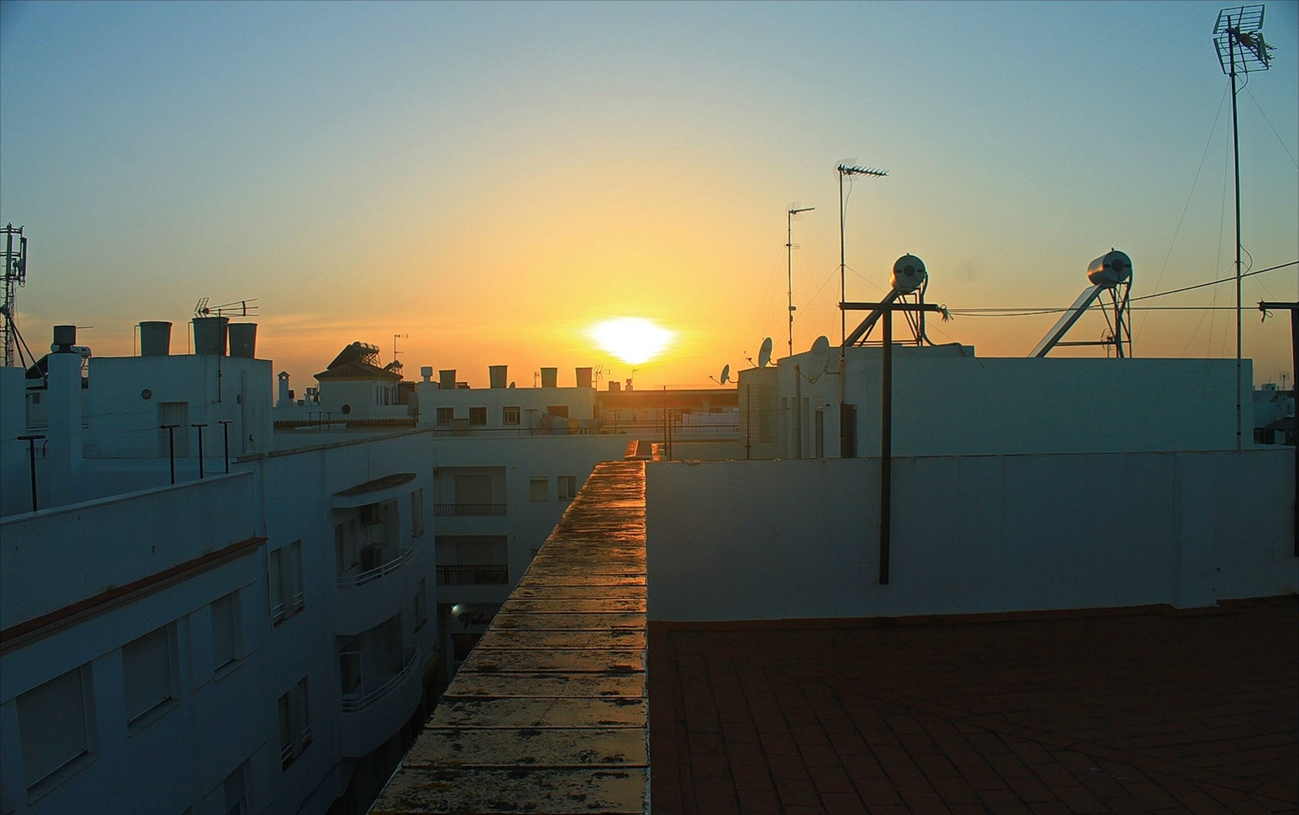 A sunset view from a rooftop terrace with buildings in the background.