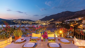 A table set for dinner with a view of a coastal town and mountains. - Your Private Paradise Above the Sea (Kalkan Antalya)