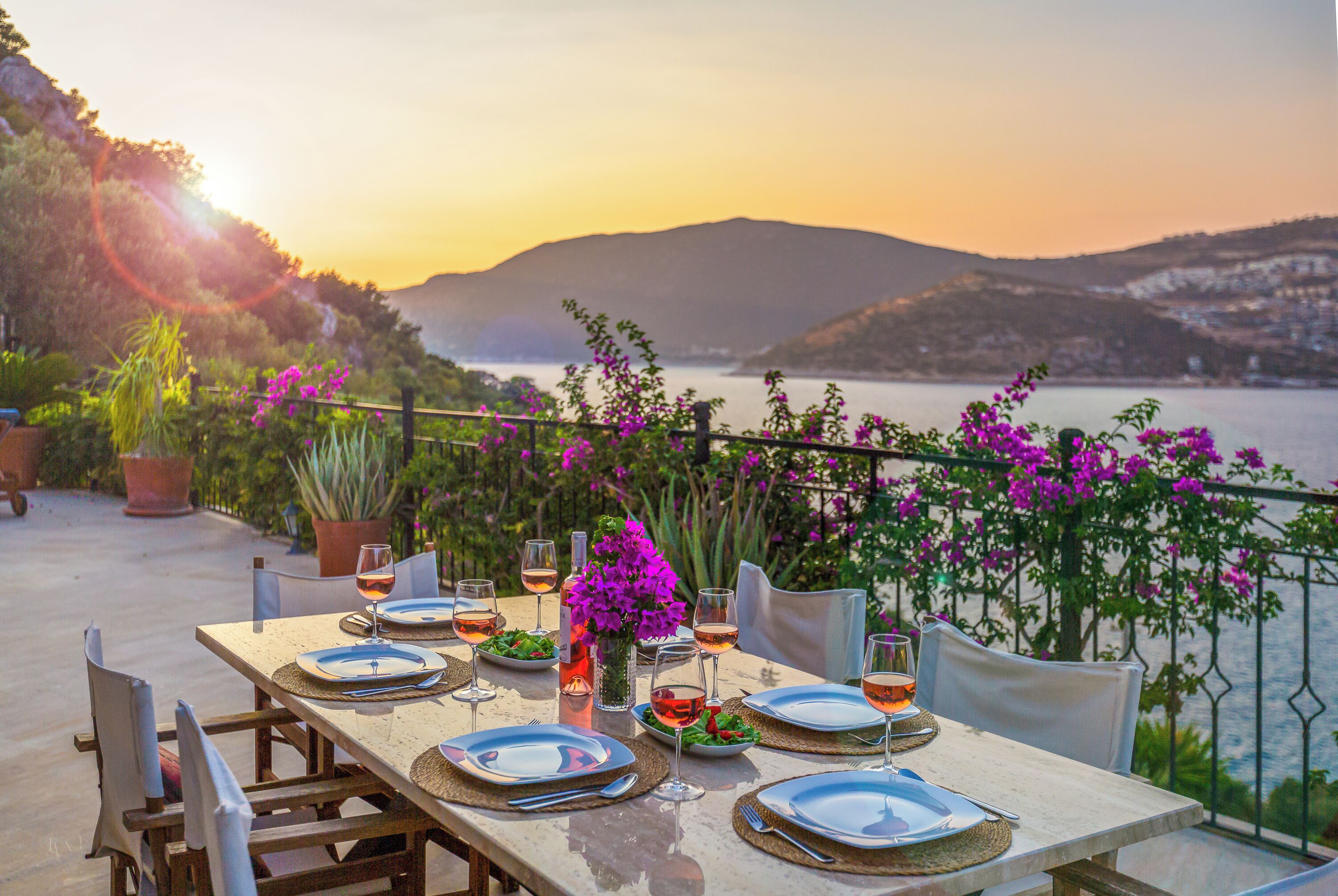 A table set for a meal with a view of a body of water and mountains in the background.