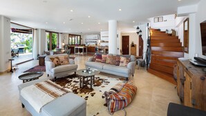 A spacious living area with a large sofa, a coffee table, and a patterned rug. A staircase with wooden steps leads to an upper level. - Your Private Paradise Above the Sea (Kalkan Antalya)