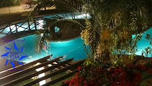 Ein Poolbereich mit Holzterrasse und Palmen, umgeben von viel Grün.