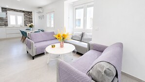 A modern living room with a sofa set, a round coffee table, and a kitchen in the background.
