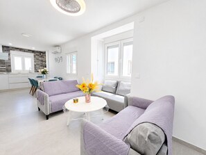A modern living room with a sofa set, a round coffee table, and a kitchen in the background.