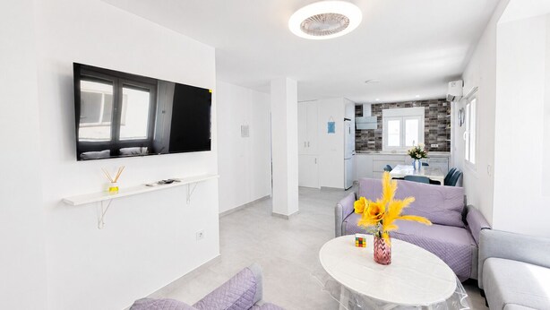 A modern living room with a flat-screen TV, a round table, and a sofa.