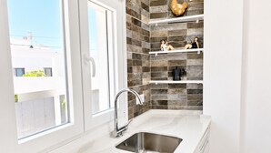 A modern kitchen with a large window, a stainless steel sink, and decorative shelves.