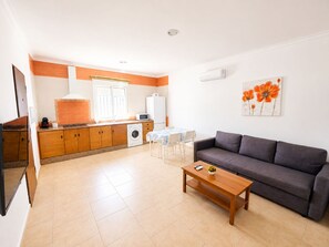 Ein kompakter Wohnraum mit Küchenzeile, einer Essecke und einer Sitzecke inklusive Sofa und Couchtisch.