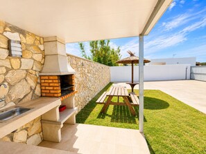 Eine Außenküche mit Steinwand, Grill und Picknicktisch.