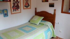 A bedroom with a wooden bed, a quilt, and framed pictures on the wall.