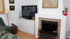 A living room with a television, fireplace, and various wall decorations.