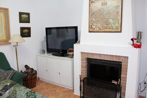 Sala de estar com televisão, lareira e diversos objetos decorativos nas paredes.