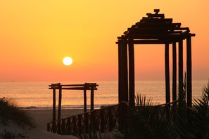 Escena de playa con un pabellón de madera y un banco de madera.
