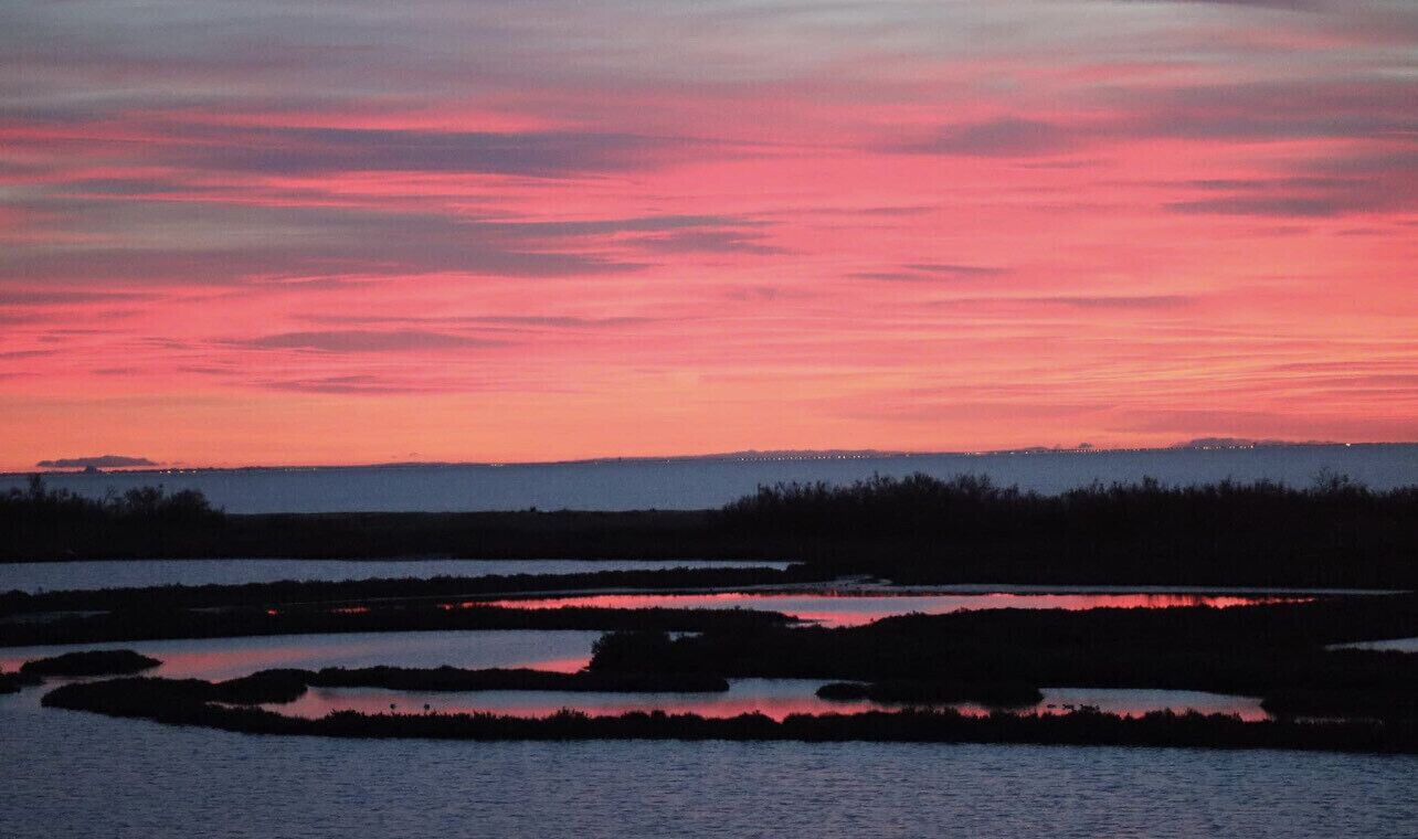 Ein Sonnenuntergang über einem Gewässer mit einer fernen Uferlinie.