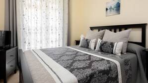 A bedroom with a bed, a TV, a nightstand, and a painting on the wall. - Holiday Rental Apartment with wifi (Marbella)
