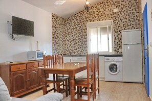 Une cuisine compacte comprenant un coin repas, un lave-linge et un téléviseur à écran plat fixé au mur.