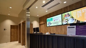 Ein Empfangsbereich mit einem Holzbüro, einem Computer und einem digitalen Bildschirm, der Informationen zeigt.