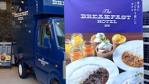 Ein blauer Lieferwagen mit dem Schriftzug "The Breakfast Hotel" und einer Speisekarte.