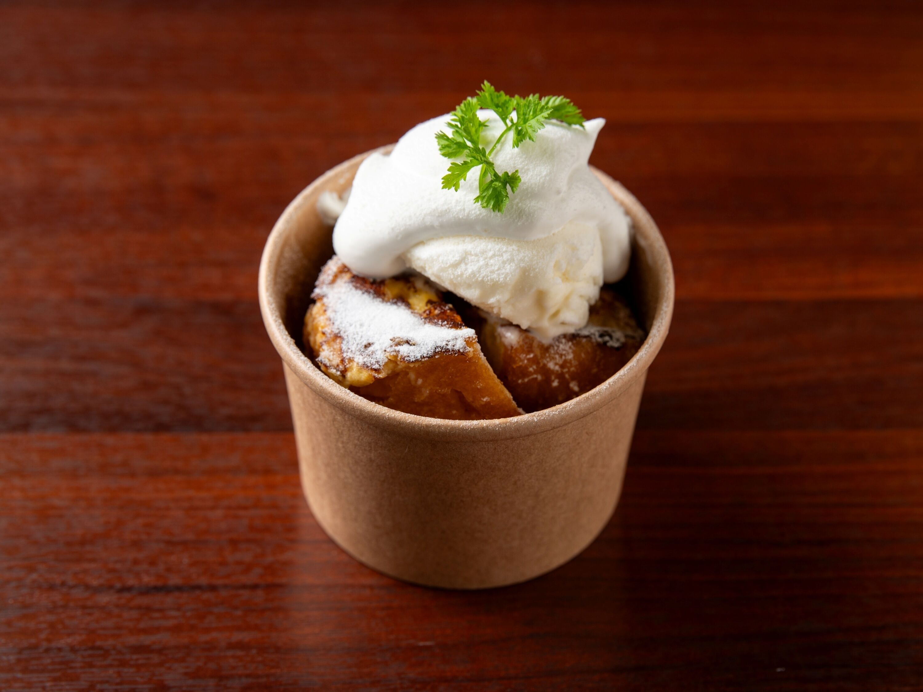 Un dessert in una piccola tazza marrone, guarnito con un rametto di prezzemolo.