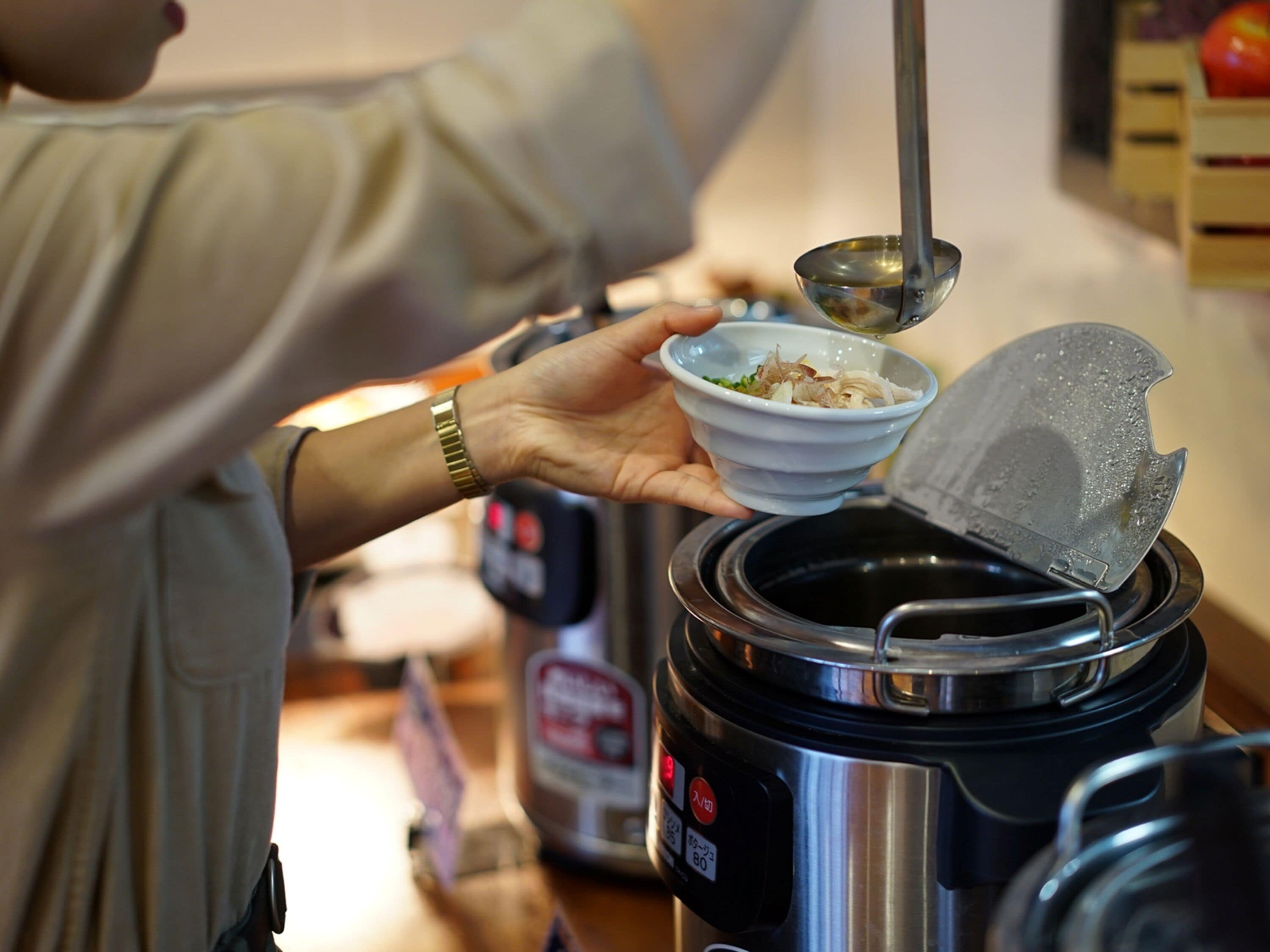 Una persona cocinando con una olla a presión, un tazón y una cuchara para servir.