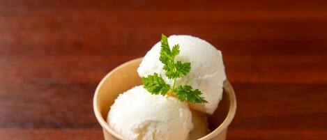 A wooden bowl containing two scoops of white ice cream garnished with a sprig of parsley.