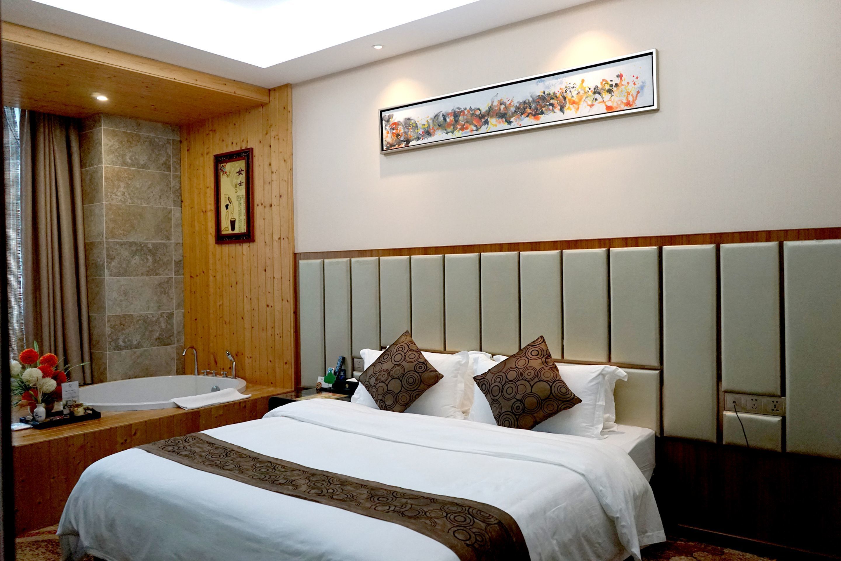 A hotel room with a large bed, a bathtub, and a wooden ceiling.