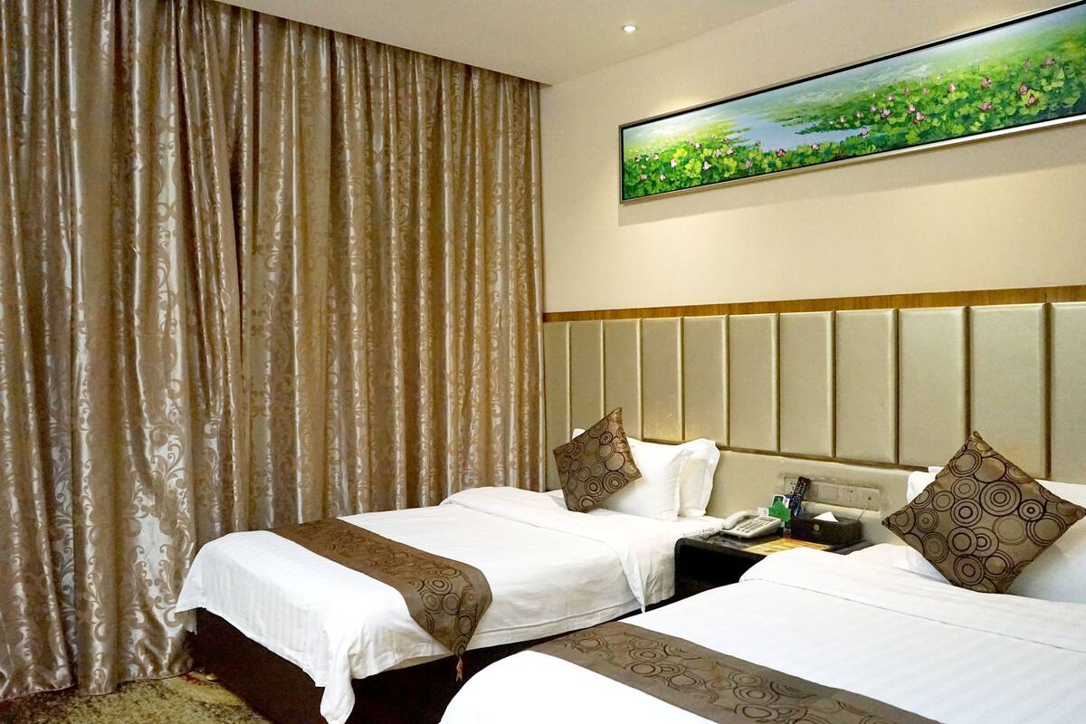 A hotel room with two beds, a headboard, a painting, and a curtain.