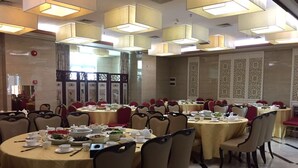 Un salón de banquetes con mesas redondas, sillas y un separador decorativo.