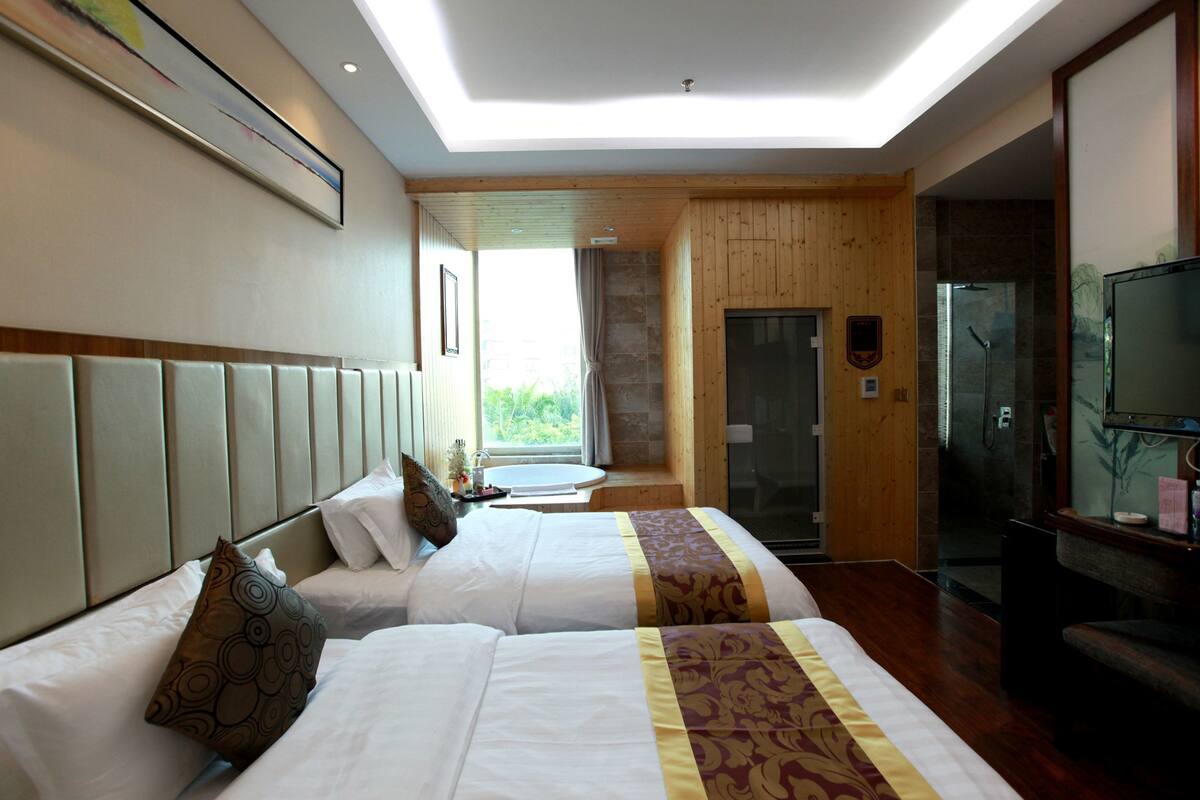 A hotel room with two beds, a TV, and a bathroom visible through an open door.