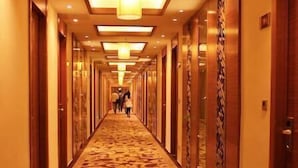 Un pasillo de hotel con alfombra estampada, puertas de madera e iluminación empotrada.