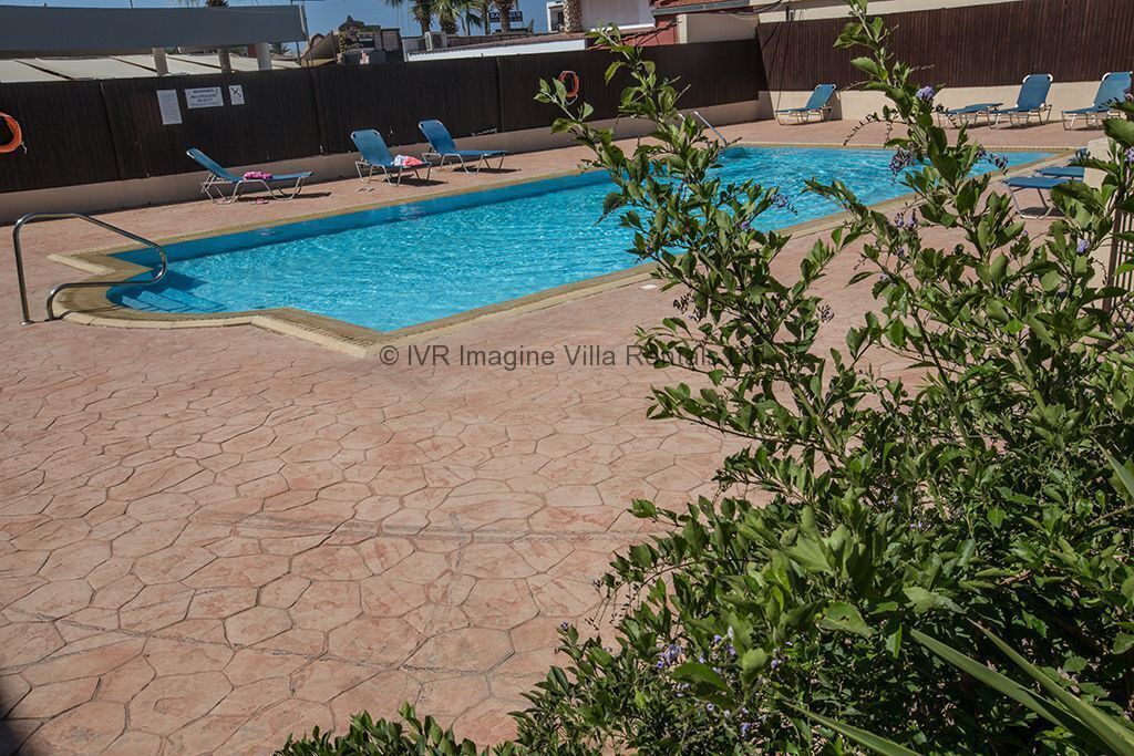 En swimmingpool med liggestole og en flisbelagt terrasse.