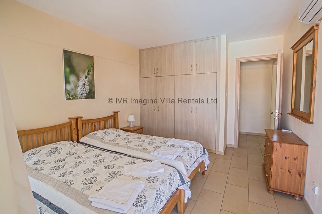 Une chambre avec deux lits, une armoire, une commode et un tableau encadré au mur.