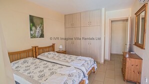 A bedroom with two beds, a wardrobe, a dresser, and a framed picture on the wall. - An apartment that sleeps 4 guests  in 2 bedrooms (Ayia Napa)