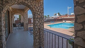 A stone-arched balcony with a pool area, outdoor furniture, and a clear view of the surrounding buildings. - An apartment that sleeps 4 guests  in 2 bedrooms (Ayia Napa)