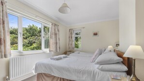 A bedroom with two beds, a window with curtains, a bedside table with a lamp, and a radiator. - Meadow View, Blue Anchor (Blue Anchor)