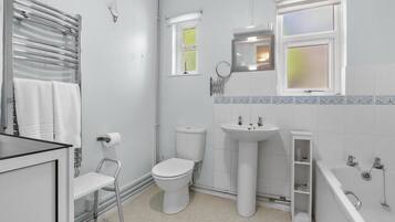 A modern bathroom with a toilet, sink, bathtub, and a window.