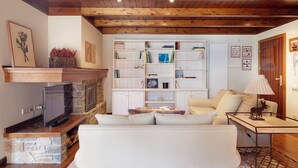 A cozy living room with a stone fireplace, white sofa, and a wooden coffee table. - Val de Ruda 46 by FeelFree Rentals (Naut Aran)