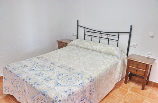 A bed with a patterned bedspread, a wooden nightstand, and a metal headboard.