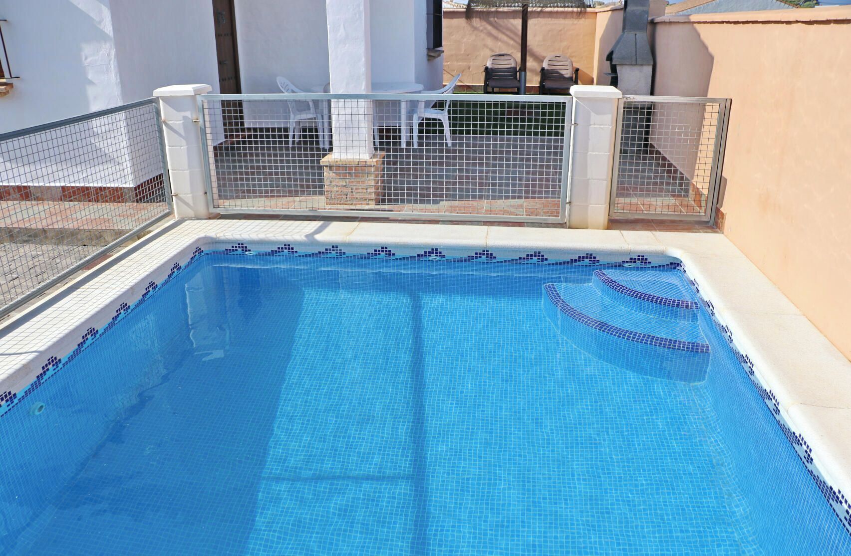 Ein rechteckiger Pool mit einer gefliesten Kante und einem Metallzaun drumherum.